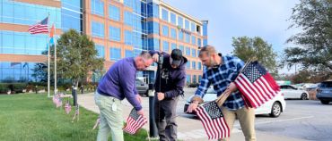 Netsmart associates planting flags in green lawn across from office building